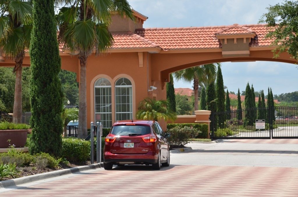 A red car parked in front of a building with a red-tiled roof and arched entrance.