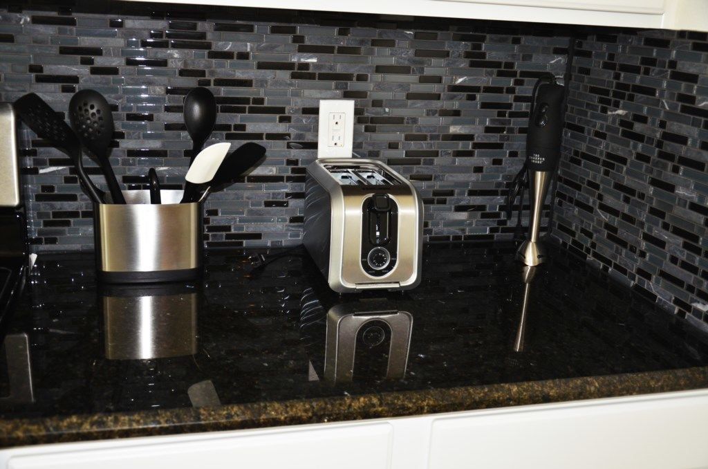 A kitchen counter with a toaster, a container of utensils, and a blender.