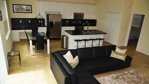 A modern kitchen with a black countertop, stainless steel appliances, and a dining area with a glass table and chairs.