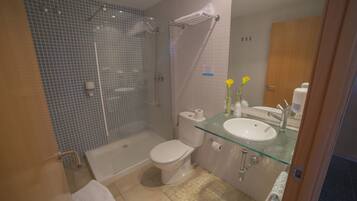 A modern bathroom with a glass shower enclosure, a white toilet, and a glass sink.