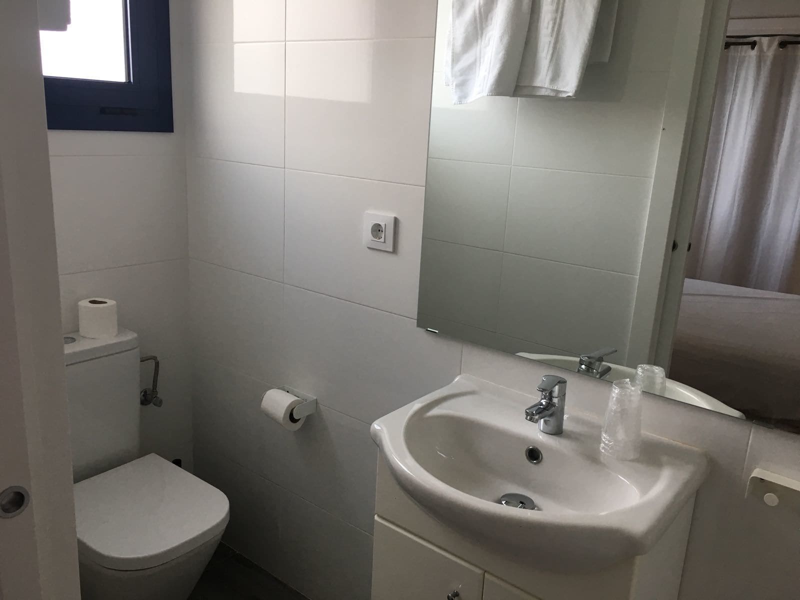 Een badkamer met toilet, wastafel, spiegel en raam.