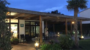 A covered outdoor seating area with chairs and tables, a wooden pergola, and potted plants. - Casa Del Mar Hotel (Roses)