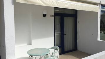 A balcony with a glass door, a small table, and a chair.