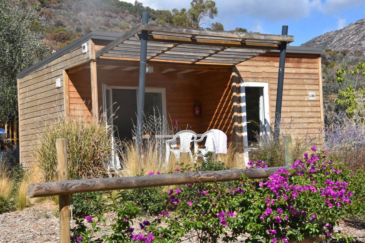 Una cabaña de madera con un porche cubierto, un extintor y un cartel con un número que indica su ubicación.