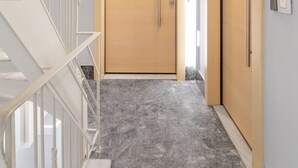 A hallway with a wooden door, a staircase with white railings, and a marble floor. - Acropolis Suites 1 - Where else in Athens (Athens)