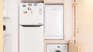 A compact kitchen with a refrigerator, washing machine, and wooden cabinets. - Acropolis Suites 1 - Where else in Athens (Athens)