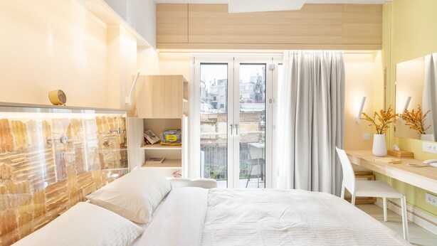 A modern hotel room with a large bed, a desk, and a balcony with curtains. - Acropolis Suites 1 - Where else in Athens (Athens)