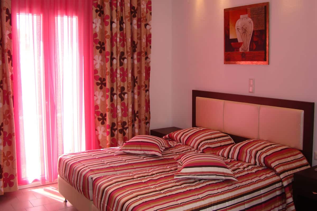 Un dormitorio con cama, cortinas y un cuadro en la pared.