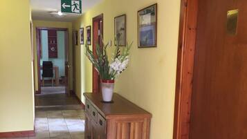 A hallway with a wooden bench, a potted plant, and a door with a plaque.