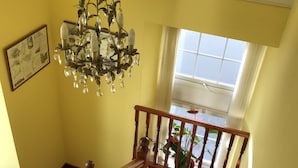 A staircase with wooden balusters and a floral carpet, leading to a room with yellow walls and a chandelier. - Pisgah Guest House Snowdonia (Blaenau Ffestiniog)