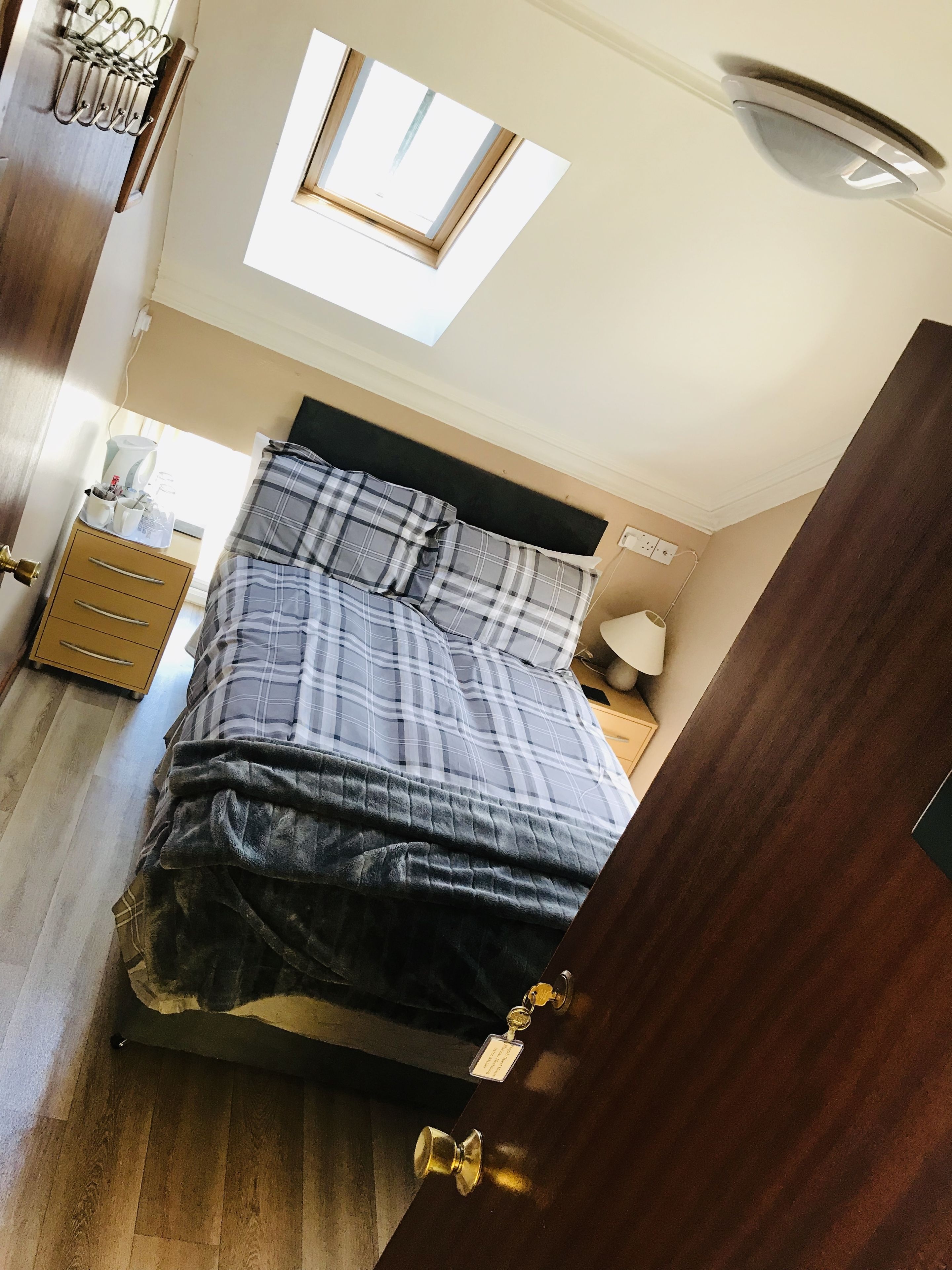 A bedroom with a bed, a bedside table, a lamp, a window, and a ceiling fan.