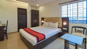 Una habitación de hotel con cama, escritorio, silla y ventana con persianas.