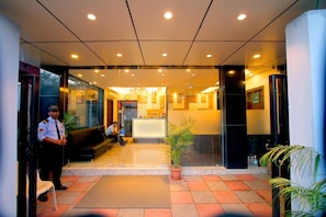 A hotel lobby with a reception desk, a waiting area, and a security guard. - Hotel Crest Inn (Kolkata)
