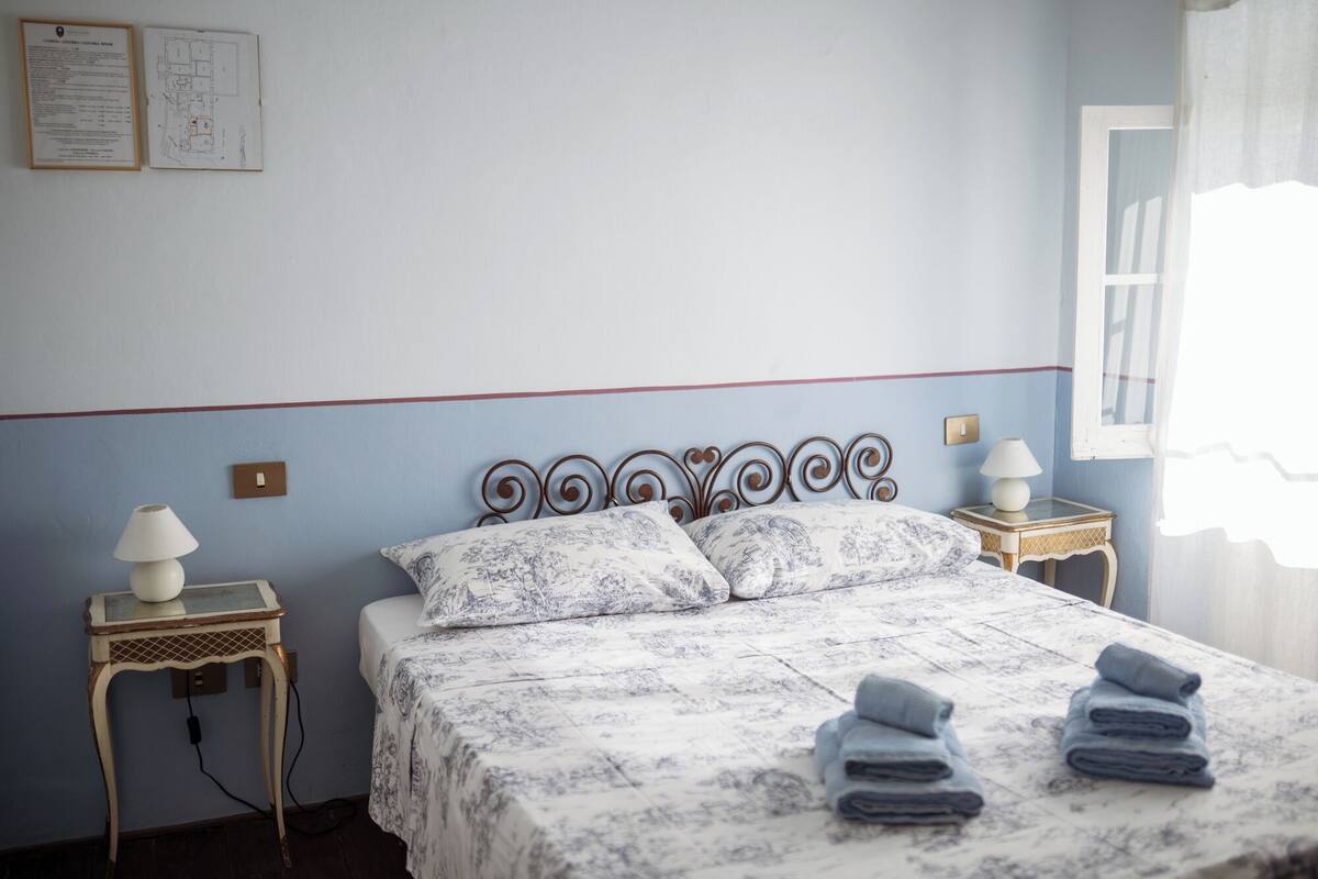 A bedroom with a bed, two bedside tables, and a window.