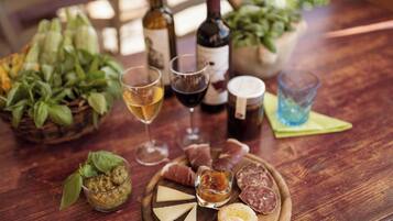 Una mesa de madera con una tabla de embutidos, copas de vino y una botella.