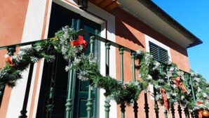 Fachada de edificio con baranda de metal verde, una puerta y una ventana.