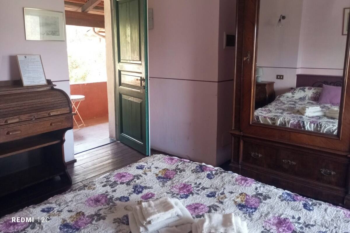 A bedroom with a bed, a dresser, a mirror, and a door leading to an outdoor area.