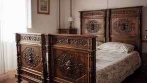 Un dormitorio con dos camas de madera con intrincados grabados, una mesita de noche y un tocador.