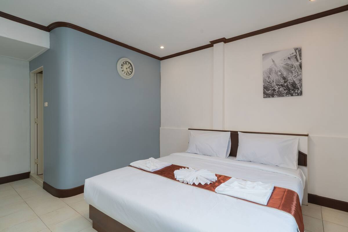 Une chambre d’hôtel avec un lit, une horloge et un tableau encadré au mur.