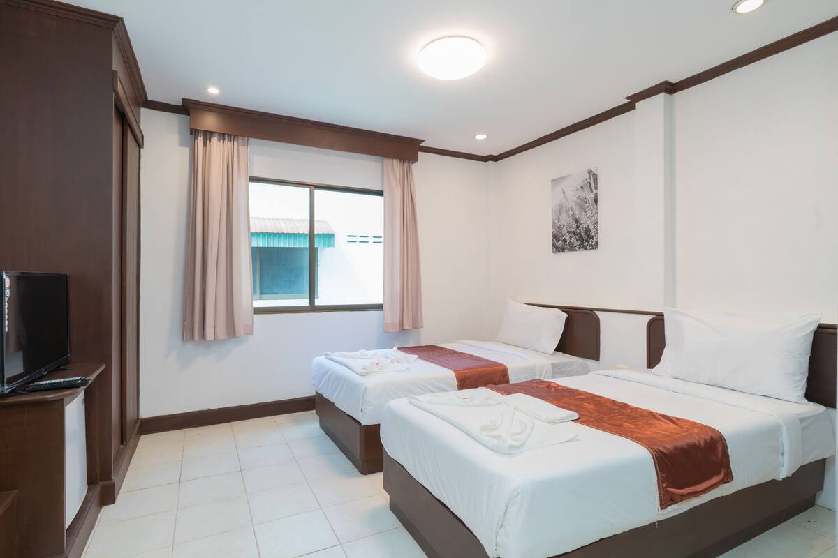Une chambre d’hôtel avec deux lits, une télévision et une fenêtre avec des rideaux.