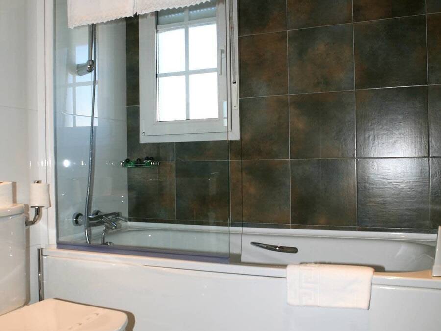 Un baño con ducha de vidrio, inodoro blanco y bañera con toalla.