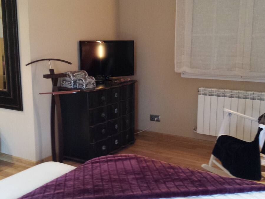 Una habitación pequeña con una cama, una silla, un aparador y un radiador.