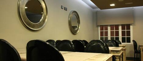 A room with round mirrors on the wall, a row of black chairs, and a window with a view of the outside.