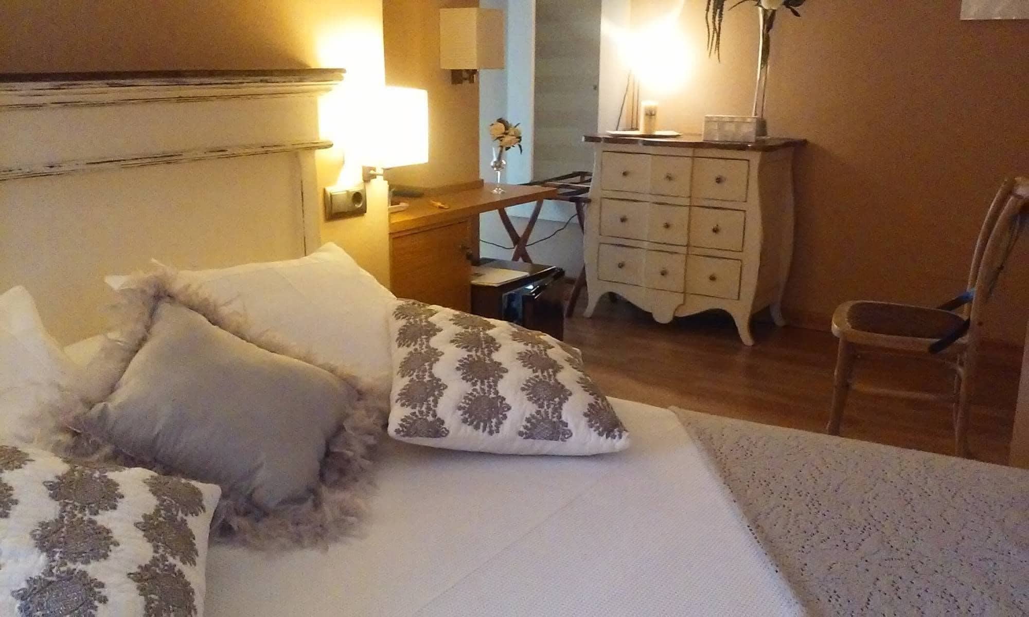A bedroom with a bed, bedside table, dresser, and chair.