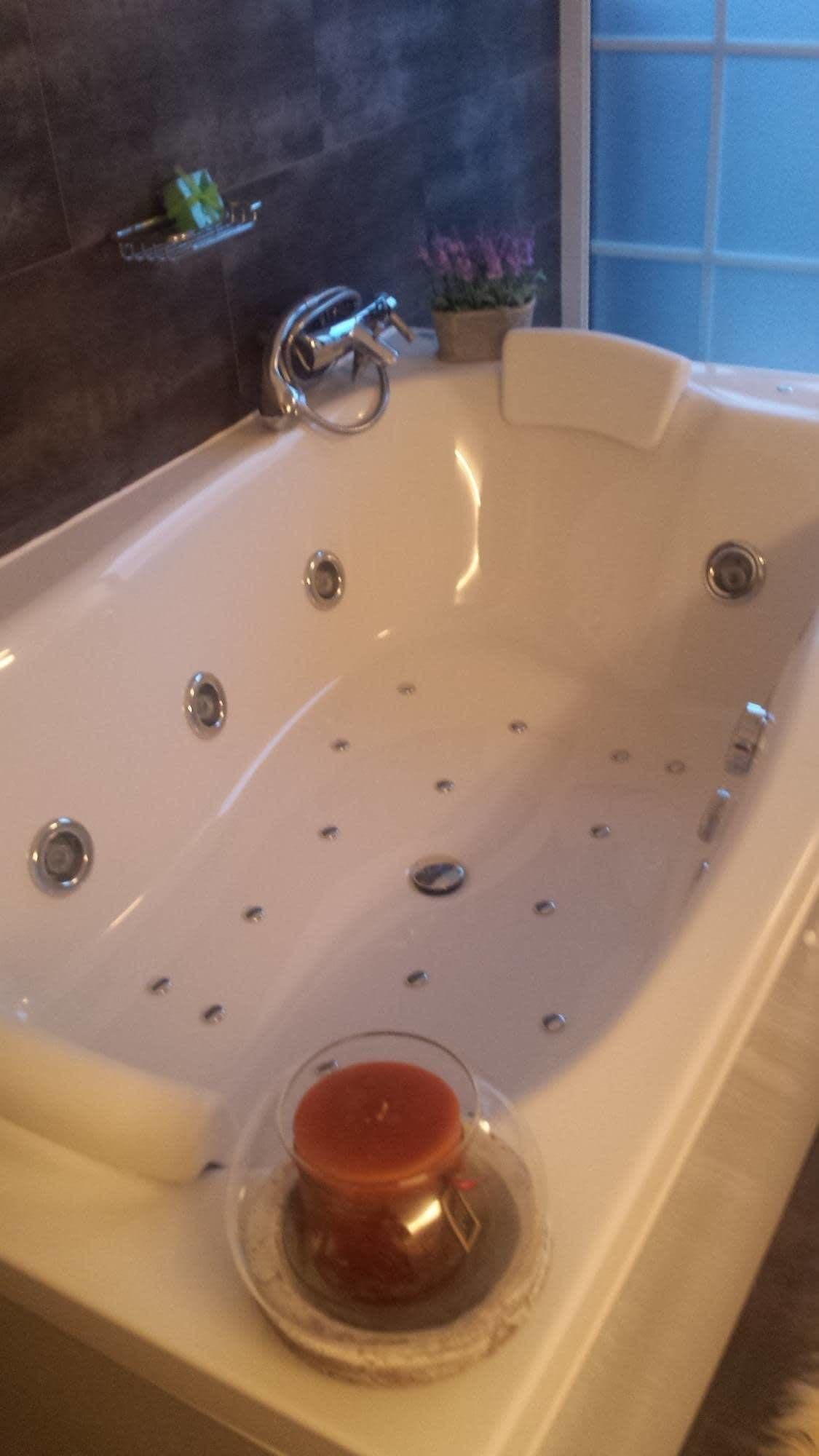 A large, empty bathtub with a glass candle holder in the center.