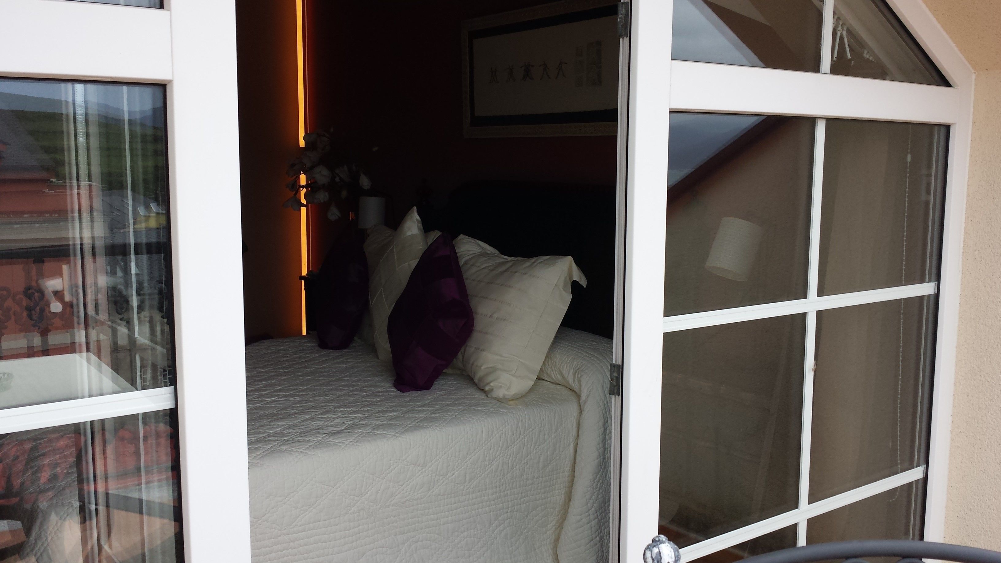 A bedroom with a bed, pillows, and a window.