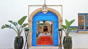 Una entrada con un arco azul, una alfombra roja y plantas en macetas a cada lado.
