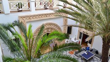 A courtyard with a palm tree, a patterned floor, and a seating area with cushions.