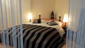 A hotel room with a bed, two bedside lamps, a nightstand, a decorative item, and a curtain partially drawn.