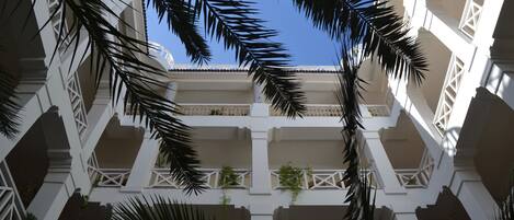 A multi-level building with white balconies and palm trees.