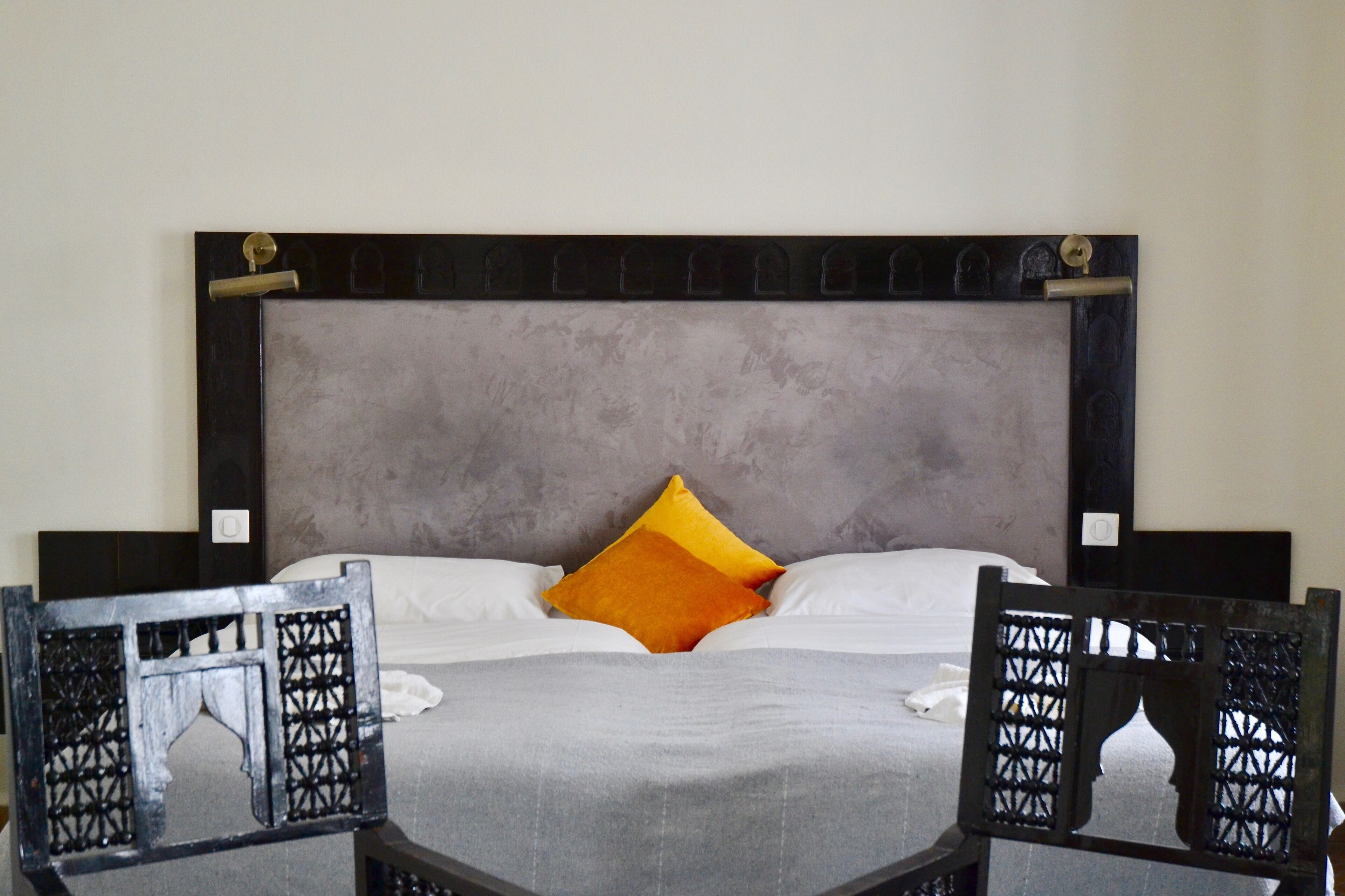 A bed with a grey headboard, two pillows, and a grey bedspread.
