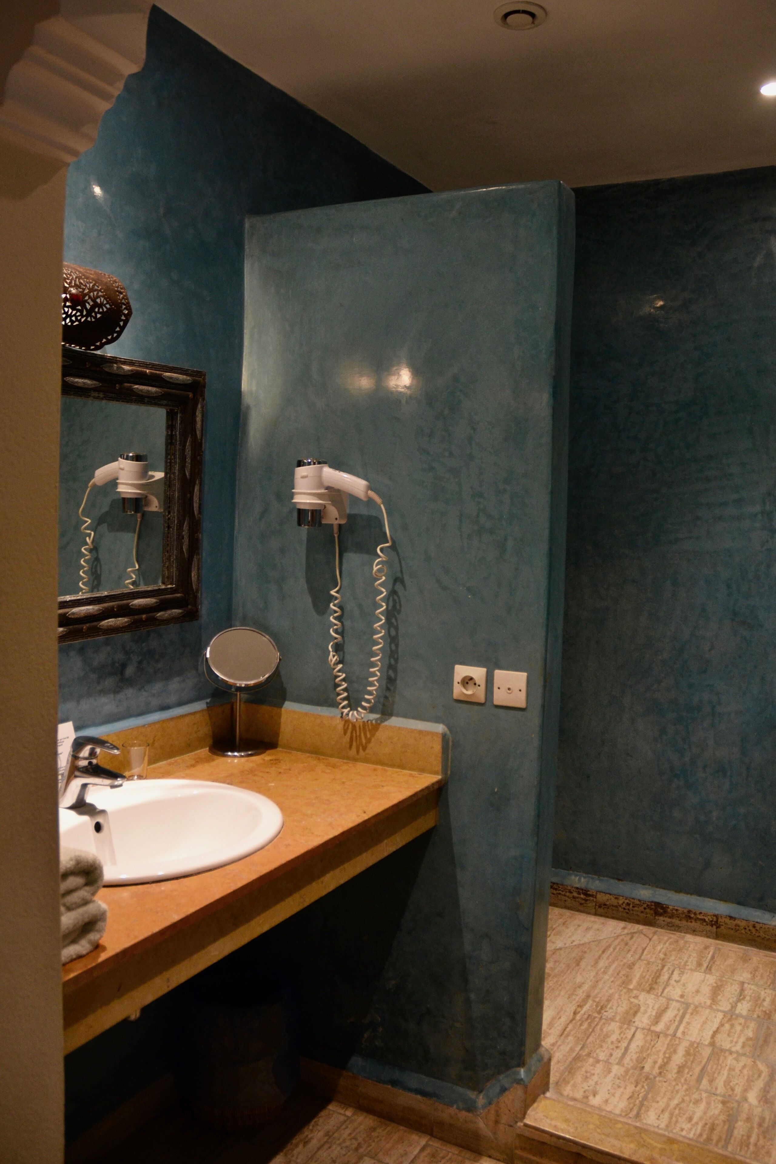 Une salle de bain équipée d’un lavabo, d’un miroir et d’un sèche-cheveux fixés au mur.
