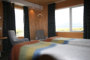Habitación de hotel con una cama grande, una silla, un escritorio y vistas al exterior.