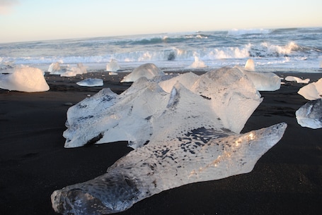 Large ice formations on a beach with the ocean in the background.