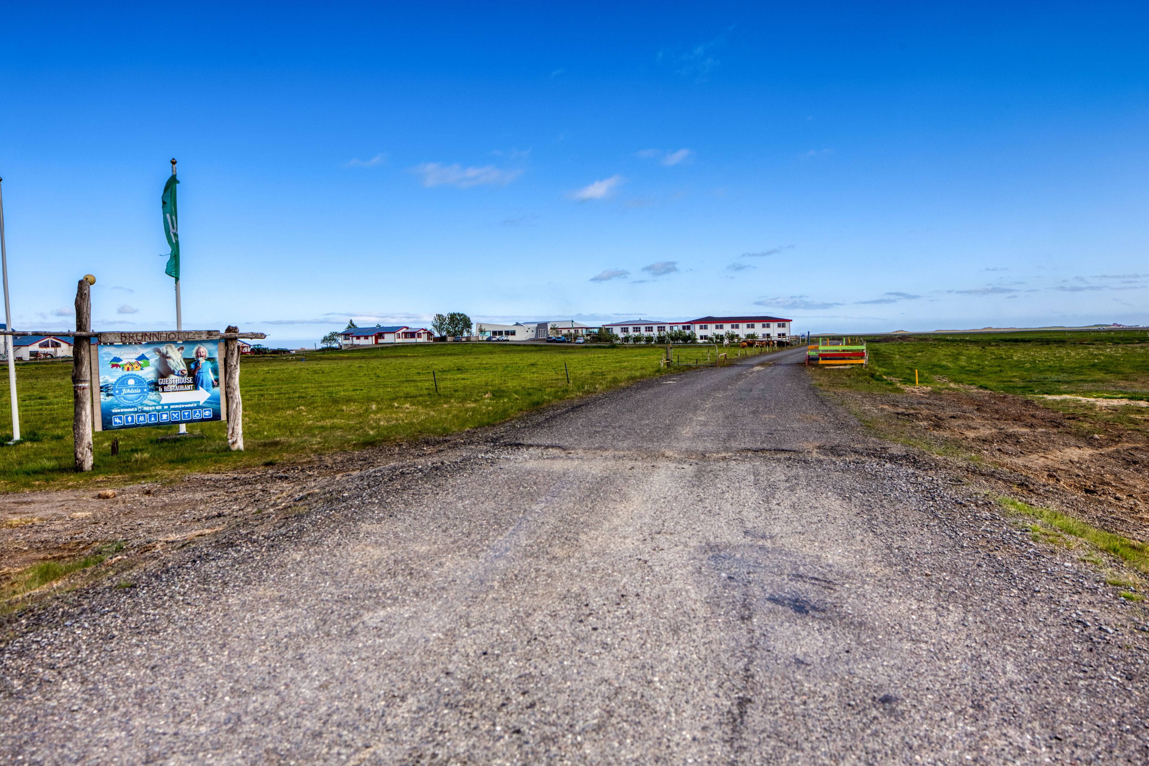A rural road leading to a building with a red roof.