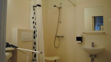 A bathroom with a shower, toilet, sink, and a hand dryer.