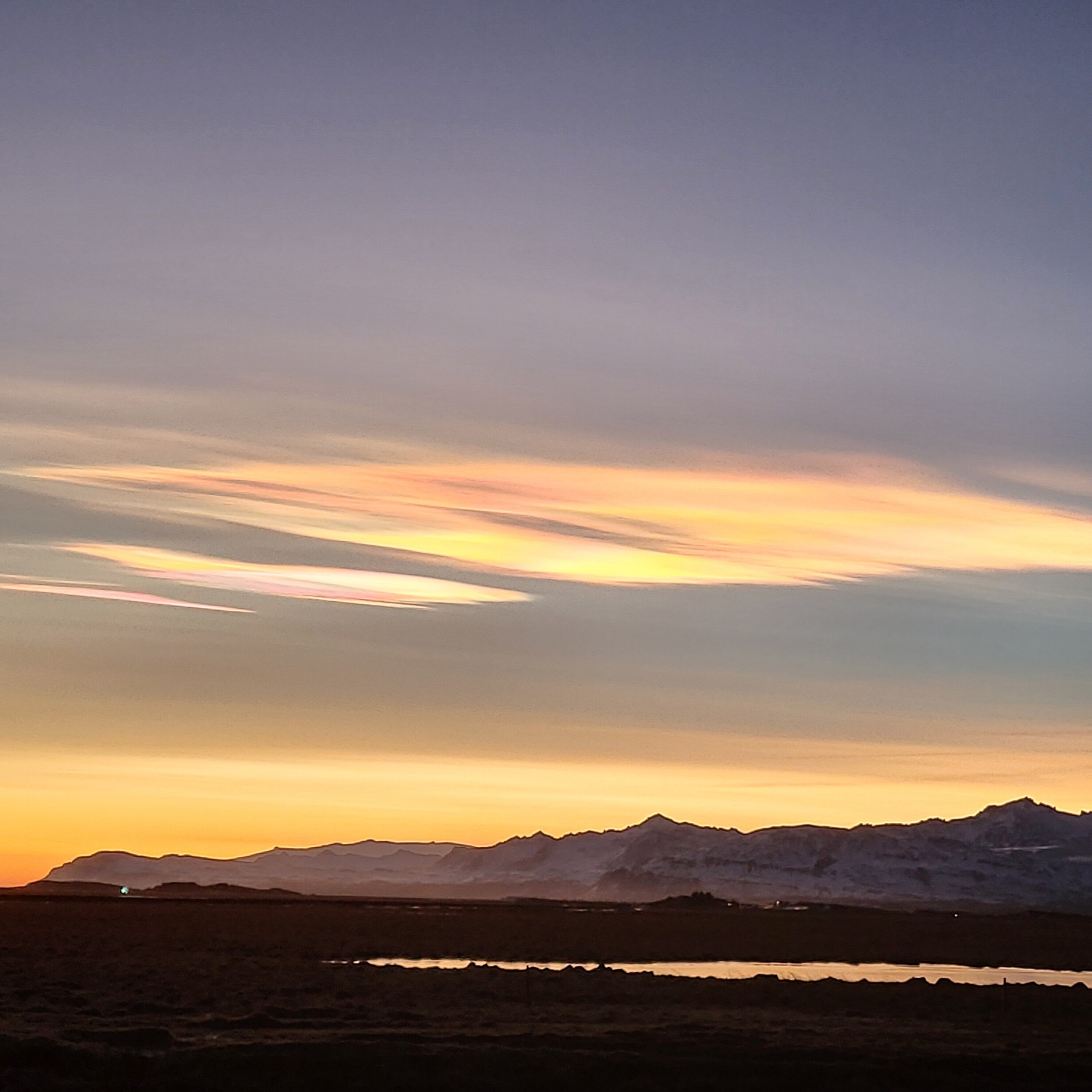 A mountain landscape at sunset with a clear sky and distant mountains.