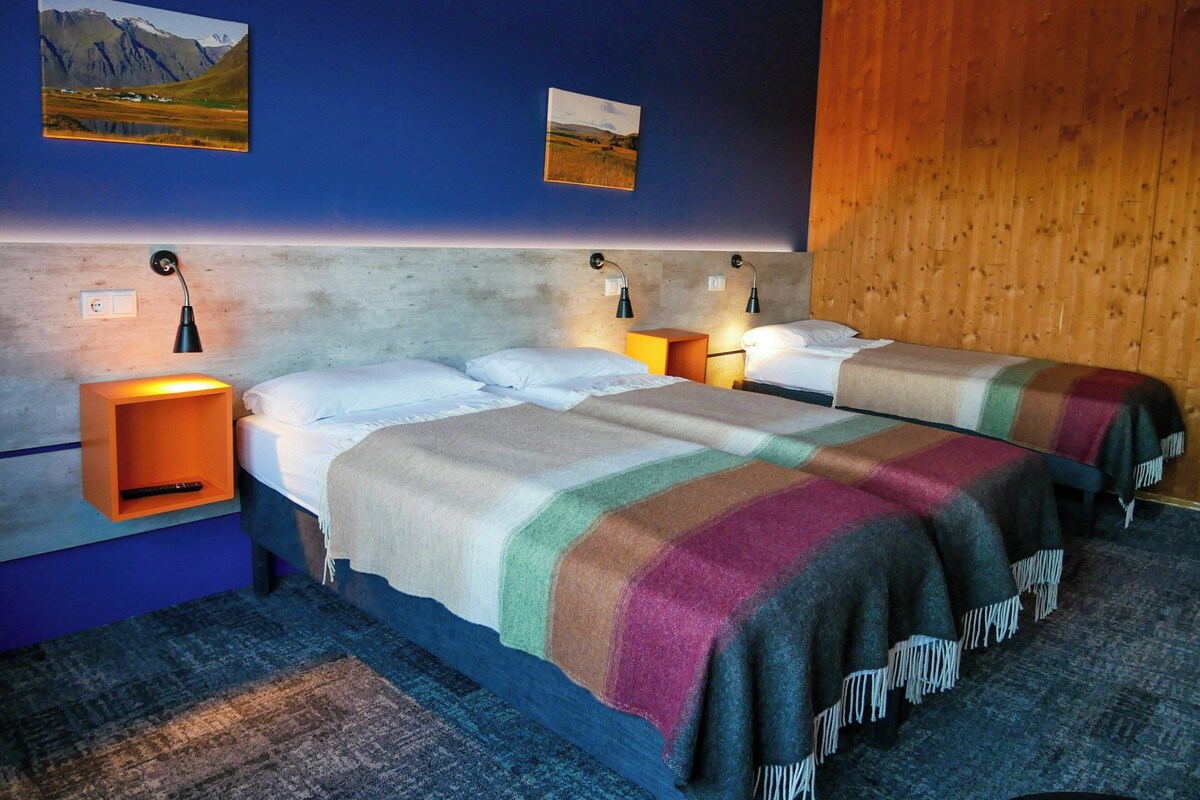 Ein Zimmer mit zwei Betten, einem Holzkopfteil und zwei Wandlampen.