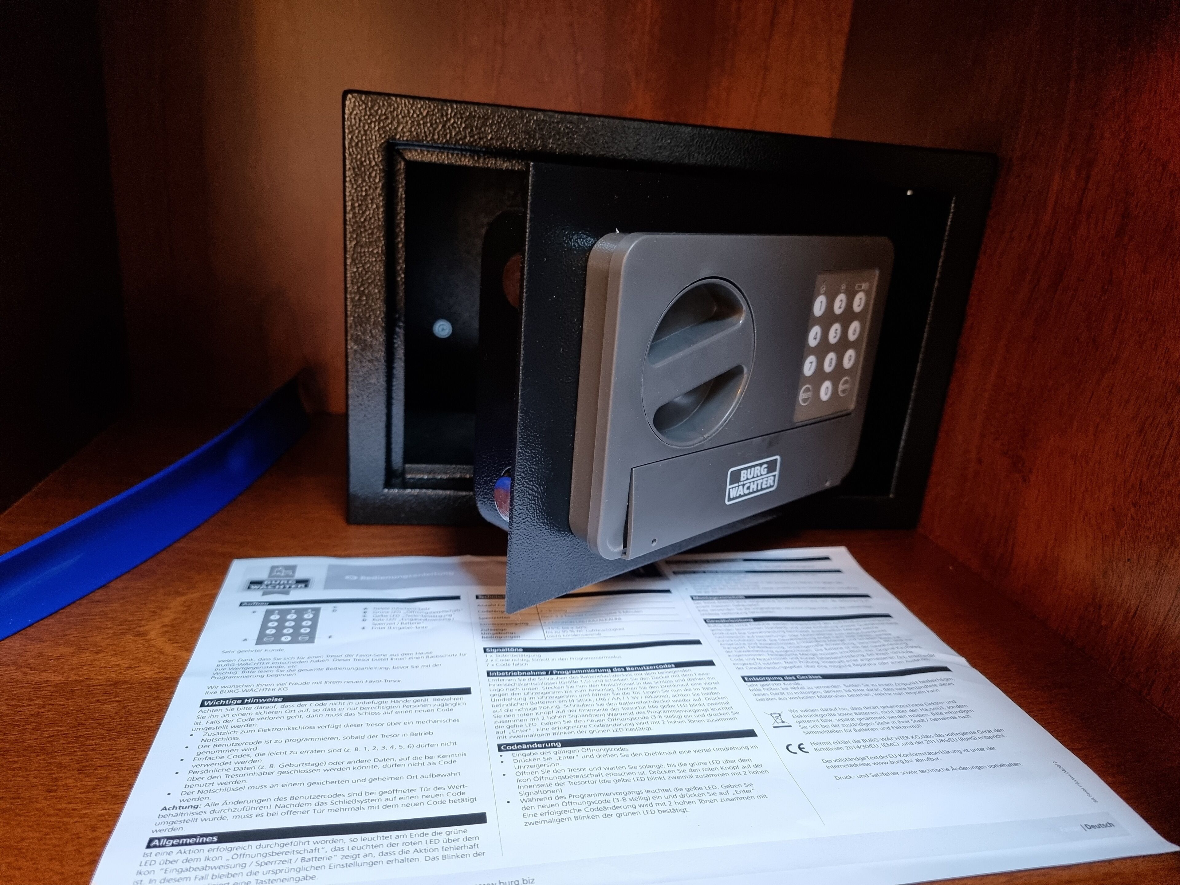 A safe with a keypad and a manual on the table.