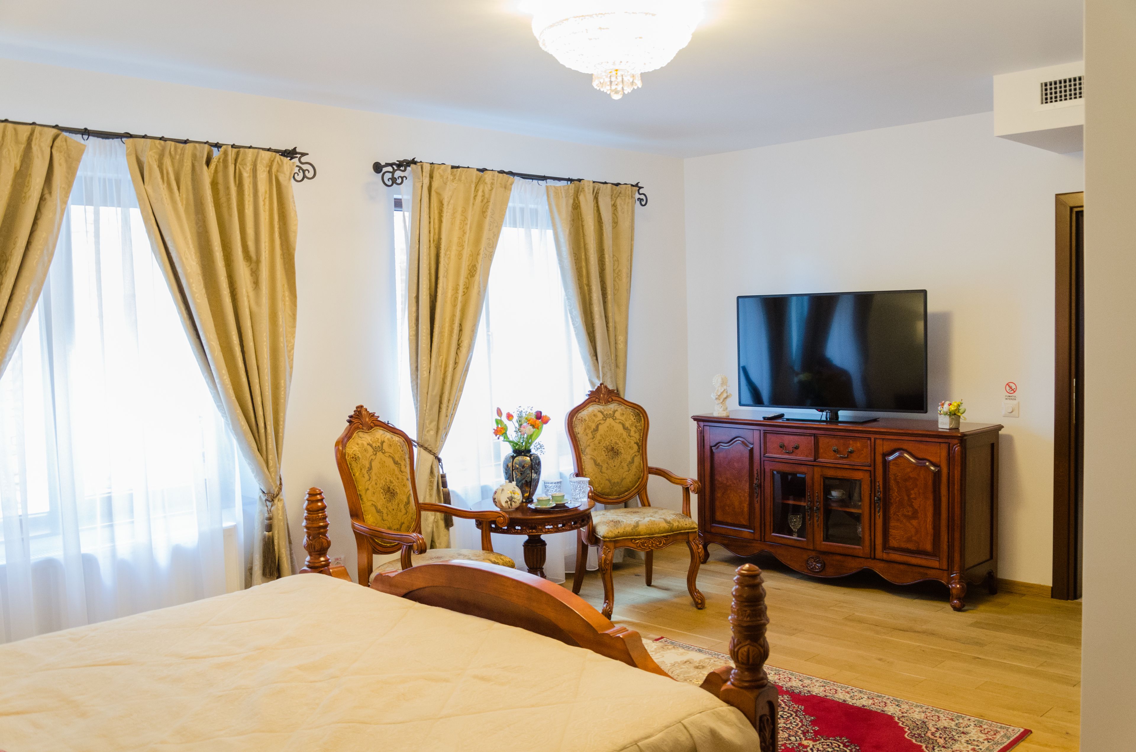 Una habitación de hotel con una cama, un televisor, un armario de madera y dos sillas.
