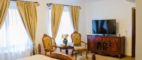 Una habitación de hotel con una cama, un televisor, un armario de madera y dos sillas.
