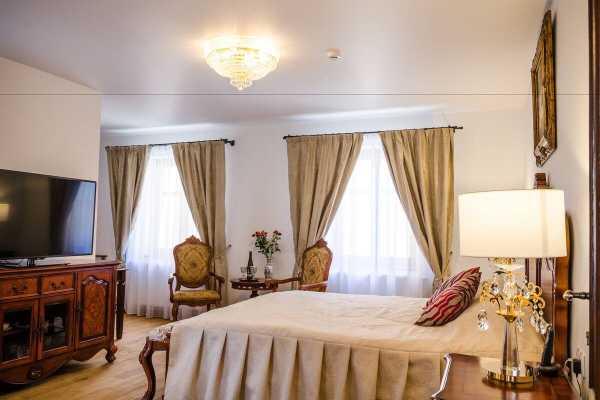 Una habitación de hotel con cama, televisión, candelabro y lámpara.