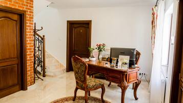 A room with a wooden desk, a chair, a television, and a staircase.