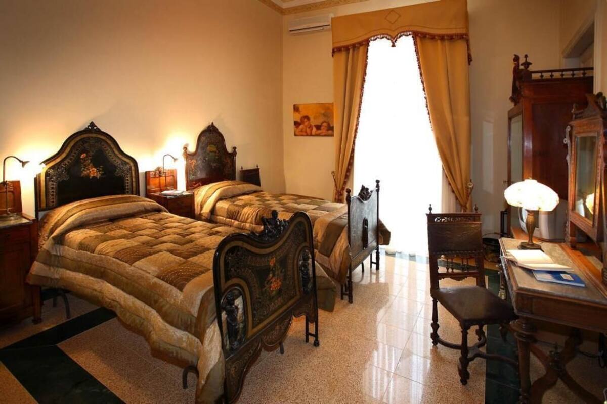 A traditional bedroom with two ornate beds, a wooden desk, and a chair.