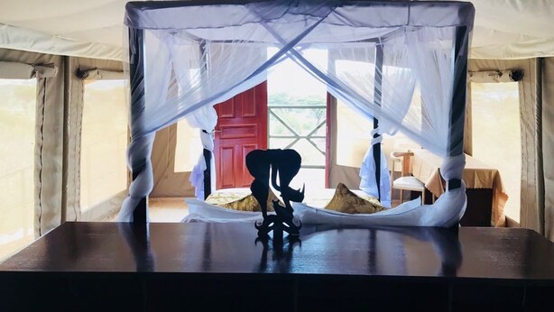 A tented room with a canopy bed, a small table, and a view of the outdoors. - La Maison Royale Masai Mara (Maasai Mara)