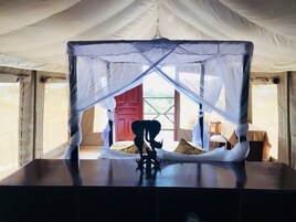 Una habitación con tienda, una cama con dosel, una mesita y vistas al exterior.